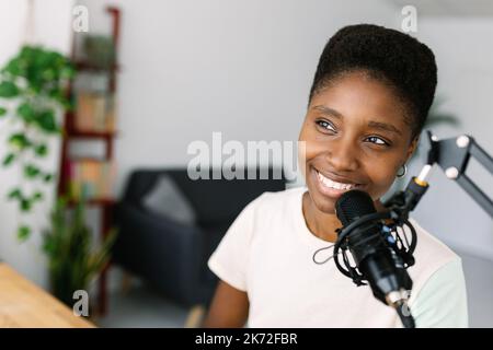 Junge afroamerikanische Content-Creator-Frau, die Podcast im Heimstudio aufnimmt Stockfoto