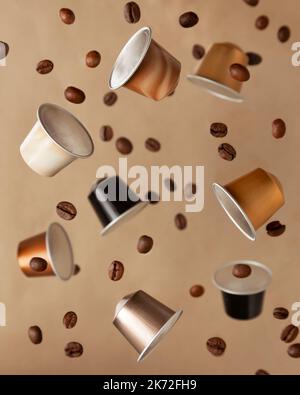Schwimmende Kaffeekapseln mit Kaffeebohnen auf braunem Hintergrund Stockfoto