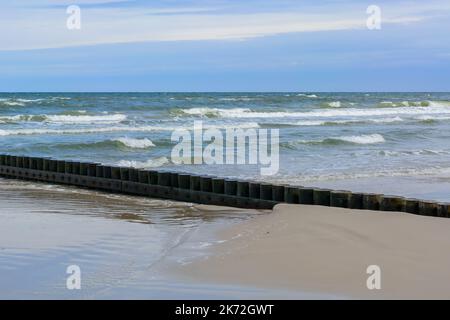 Eine hölzerne Mall aus Baumstämmen, um den Sandstrand am Meer zu schützen. Sommerurlaub. Stockfoto