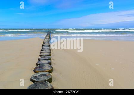 Eine hölzerne Mall aus Baumstämmen, um den Sandstrand am Meer zu schützen. Sommerurlaub. Stockfoto