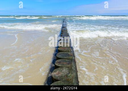 Eine hölzerne Mall aus Baumstämmen, um den Sandstrand am Meer zu schützen. Sommerurlaub. Stockfoto