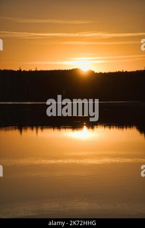 Sonnenuntergang mit Spiegelung auf einem schwedischen See in Smalland. Romantische Abendstimmung. Landschaft aus Skandinavien in der Natur aufgenommen Stockfoto