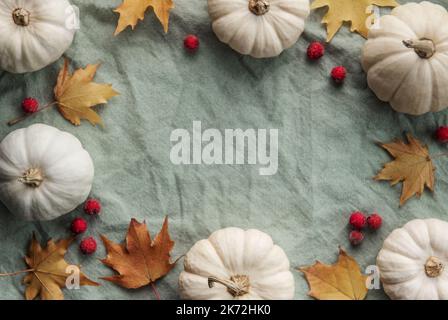 Herbstkomposition. Rahmen mit Kürbissen, getrockneten Blättern auf grünem Textilhintergrund. Herbst, Herbst, halloween, Danksagekonzept. Flach liegend, Draufsicht, Stockfoto