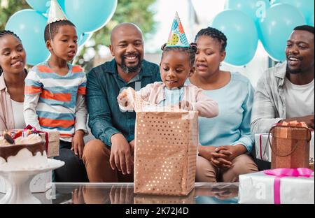 Wer hat mich dieses hier bekommen. Ein kleines Mädchen eröffnet Geschenke auf ihrer Geburtstagsparty. Stockfoto