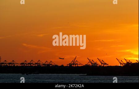Silhouette der Jersey Port Kräne und Flugzeug starten vom Newark Flughafen, Jersey, USA Stockfoto