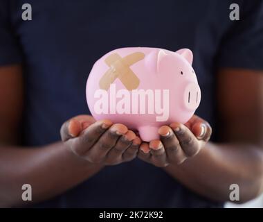 Es ist nie zu spät, um Ihre Schulden abzuzahlen. Ein nicht erkennbarer Mann, der ein Sparschwein mit einem Band hält, hilft darüber. Stockfoto