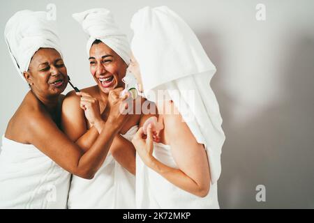 Ältere Frauen haben Spaß mit Hautpflegeprodukten - Fokus auf weibliche Mitte Gesicht Stockfoto