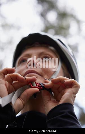 Frau, die Fahrradhelm aufsetzt Stockfoto