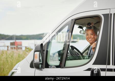 Porträt einer lächelnden älteren Frau, die im Van sitzt Stockfoto
