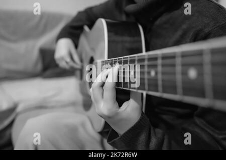 Nahaufnahme der Hände einer Frau, die eine Gitarre in Schwarz-Weiß spielen Stockfoto