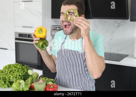 Mann spielt mit grünen Paprika in der Küche Stockfoto