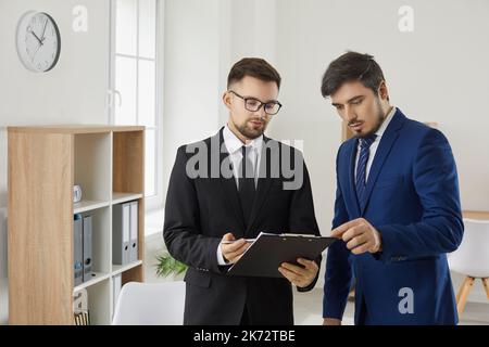 Geschäftsleute diskutieren bei einem Treffen im Büro rechtliche Dokumente, während sie an einem gemeinsamen Projekt arbeiten. Stockfoto