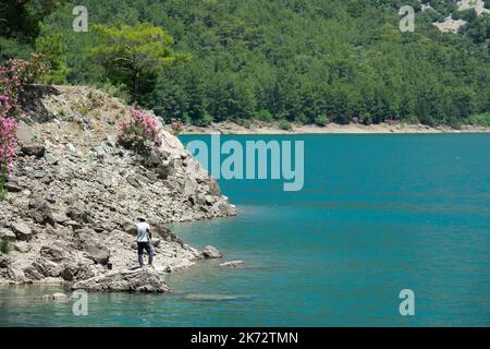 Manavgat, Türkei - 05. Juni 2019: Ein Fischer fängt Fische an einem See zwischen Bergklippen im Green Canyon Stockfoto