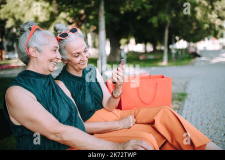 Ältere Frauen Zwillinge im Freien in der Stadt überprüfen Smartphone. Stockfoto