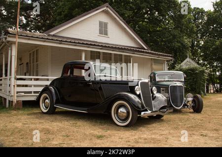 Zwei Ford Hot Rods im traditionellen Stil von 1934 vor einem Gebäude im Vintage-Stil. Stockfoto