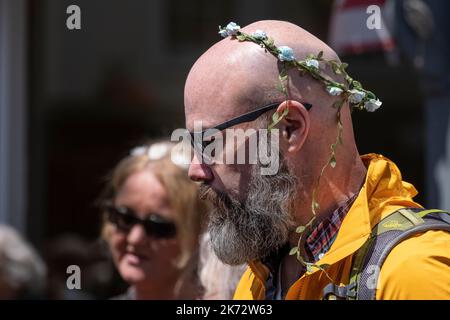 Ein bärtiger kahler Mann mit einer Blumengirlande um seinen Kopf. Stockfoto