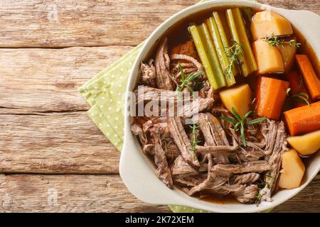 Rindfleisch-Fleisch und -Gemüse Eintopf hausgemachter Slow-Cooker-Topf Braten Sie mit Karotten, Sellerie und Kartoffeln aus der Nähe in der Schüssel auf dem Holztisch. Horizontal zu Stockfoto