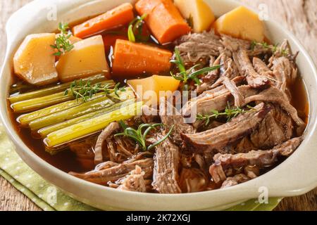 Rindfleisch-Fleisch und -Gemüse Eintopf hausgemachter Slow-Cooker-Topf Braten Sie mit Karotten, Sellerie und Kartoffeln aus der Nähe in der Schüssel auf dem Holztisch. Horizontal Stockfoto