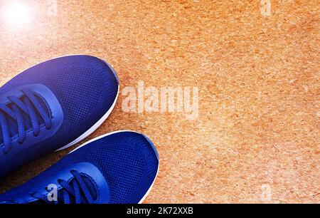 Flach Legen Sie ein Paar blaue Sportschuhe auf einem braunen Korkgrund. Konzept gesunder Lebensstil und Sport. Stockfoto