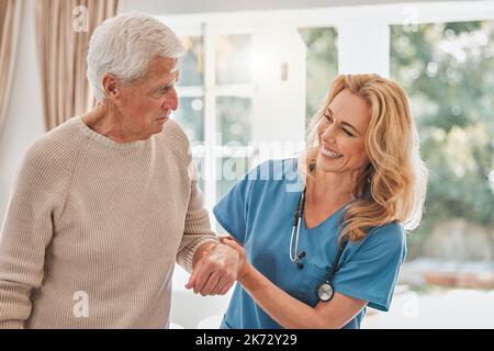Sie werden von Tag zu Tag stärker. Eine Krankenschwester hilft ihrem männlichen Patienten beim Gehen. Stockfoto