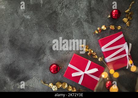 Weihnachtskomposition mit Dekoration - goldene Zweige, Geschenke und Lichter mit Bokeh im Dunkeln. Flach liegend Stockfoto