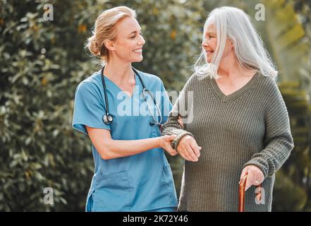 Es ist ein wunderbarer Tag für einen Spaziergang. Eine Krankenschwester, die mit ihrer älteren Patientin frische Luft bekommt. Stockfoto