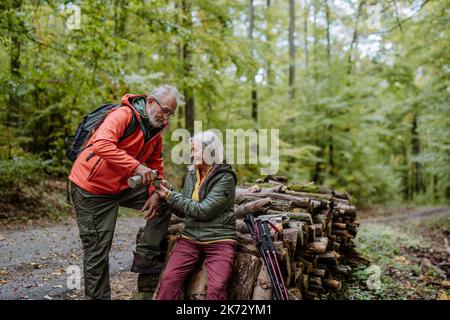 Seniorenpaar, das beim Wandern im Herbstwald Pause gemacht hat. Stockfoto