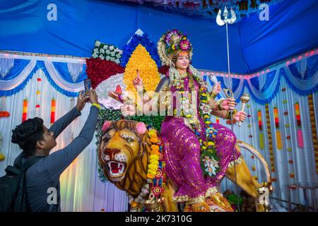 Ein Mann, der auf ein Bild eines Idols von Maa Durga in einem mandal in Mumbai für das verheißungsvolle indische Festival von Navratri klickt Stockfoto