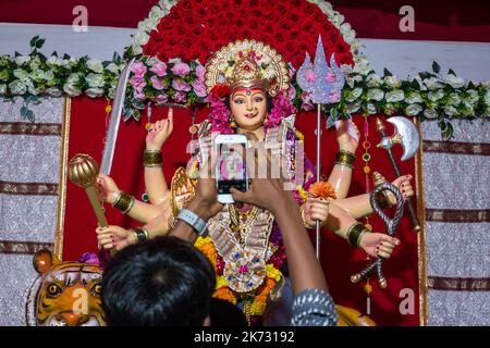 Ein Mann, der auf ein Bild eines Idols von Maa Durga in einem mandal in Mumbai für das verheißungsvolle indische Festival von Navratri klickt Stockfoto