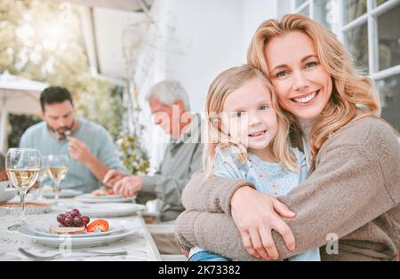 Die Dinge, die wichtig sind, sind Glaube, Familie und Freunde. Eine Mutter umarmte ihre Tochter bei einem Familienessen zu Hause. Stockfoto