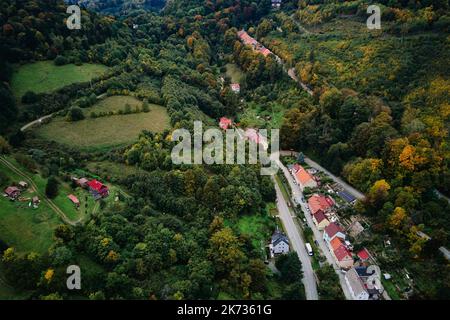 Drohnenflug über die Landschaft mit Bergdorf und landwirtschaftlichen Feldern in der Herbstsaison. Herbstliche Naturlandschaft Stockfoto