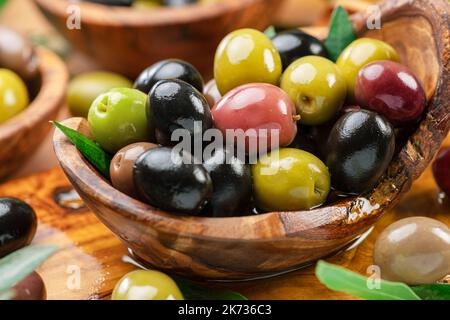 Kalamata, grüne und schwarze Oliven in der Holzschale. Hintergrund der Speisen. Stockfoto