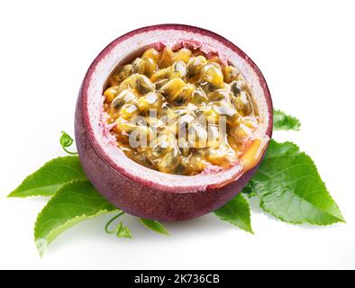 Die Hälfte der dunkelvioletten Passionsfrucht mit zwielichtiger Innenseite liegt auf grünen passiflora-Blättern auf weißem Hintergrund. Stockfoto