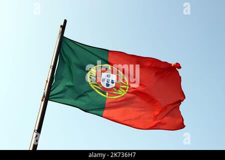 Rote und grüne portugiesische Flagge winkt im Wind, gegen blauen Himmel Stockfoto