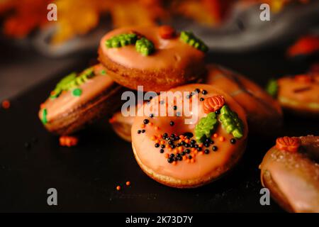 Hausgemachte Mini-Herbst-Donuts mit orangefarbenem Zuckerguss, selektivem Focu Stockfoto