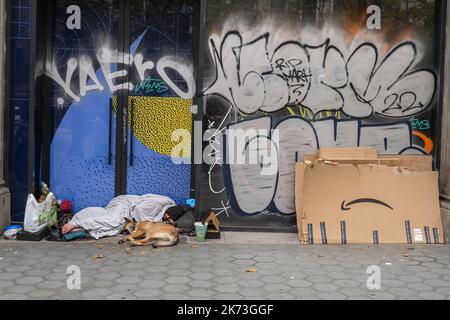 Barcelona, Spanien. 17. Oktober 2022. Ein obdachloser Mann, der in Passeig de Gràcia neben einem Amazon-Paket schläft und von seinem Haustier begleitet wird. Anzeichen von Betteln und Armut in Barcelona am Internationalen Tag zur Beseitigung der Armut, der von den Vereinten Nationen seit 1992 anerkannt wird. Kredit: SOPA Images Limited/Alamy Live Nachrichten Stockfoto