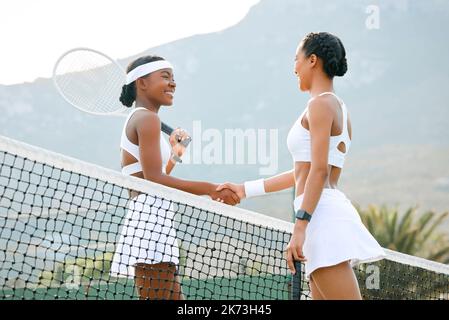 Alles gute auf dem Platz heute. Zwei sportliche Frauen schütteln sich die Hände, während sie gemeinsam auf einem Platz Tennis spielen. Stockfoto