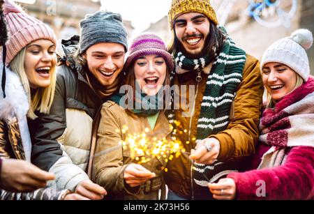 Jungs und Mädchen besten Freunde jubeln mit Wunderkerzen auf warmer Mode Kleidung - Happy Life Style Konzept mit milenial Menschen Spaß zusammen outdoo Stockfoto