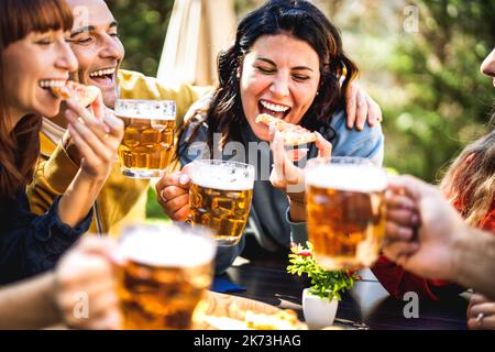 Fröhliche Freunde essen Pizza im Biergarten - Beverage Life Style Konzept mit jungen Leuten, die gemeinsam trinken und Spaß in der Brauerei haben Stockfoto