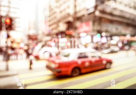 Verschwommener defokussierte abstrakte Hintergrund des roten Taxi auf Zebrastreifen mit sanftem rosa Pastellfilter - überfüllte Nathan Road Straße in Hong Kong City ce Stockfoto