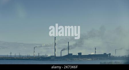 Industrielandschaft mit starker Verschmutzung durch eine große Fabrik. Rohre auf dem Gebiet der Anlage. Stockfoto