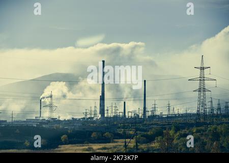 Industrielandschaft mit starker Verschmutzung durch eine große Fabrik. Rohre auf dem Gebiet der Anlage.