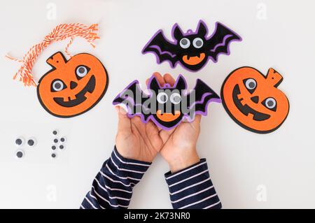 halloween Dekorationen in Kinderhände über weißem Tisch Stockfoto