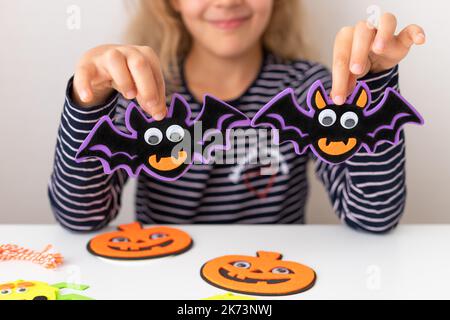 Kleines Mädchen hält Halloween Fledermäuse Dekorationen mit gruseligen Gesicht Stockfoto