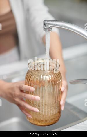Nahaufnahme einer Frau, die frisches Wasser in eine Glasvase gießt Stockfoto