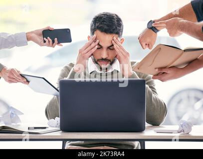 Diese Leute geben mir Kopfschmerzen. Ein hübscher junger Geschäftsmann sitzt im Büro und fühlt sich gestresst, während seine Kollegen Druck ausüben Stockfoto