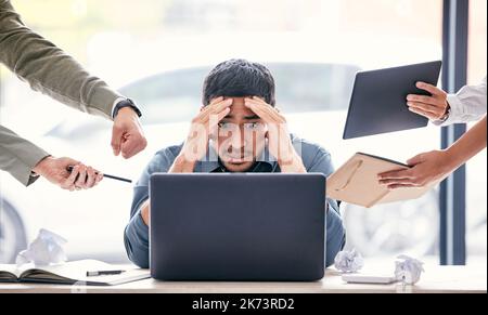 Ich werde aufhören. Ein hübscher junger Geschäftsmann sitzt im Büro und fühlt sich gestresst, während seine Kollegen Druck auf ihn ausüben. Stockfoto