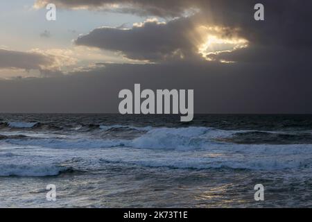 Sonnenuntergang mit einem Loch in den bewölkten Himmel und Sonnenstrahlen. nordportugiesische Küste vor Sturm. Stockfoto