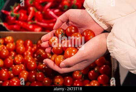 Eine Frau wählt in einem Lebensmittelgeschäft Cherry Tomatoes aus der Nähe. Stockfoto