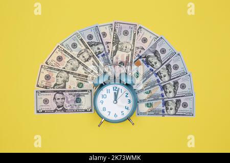Wecker und Geld auf farbigem Hintergrund, Minimalismus. Stockfoto
